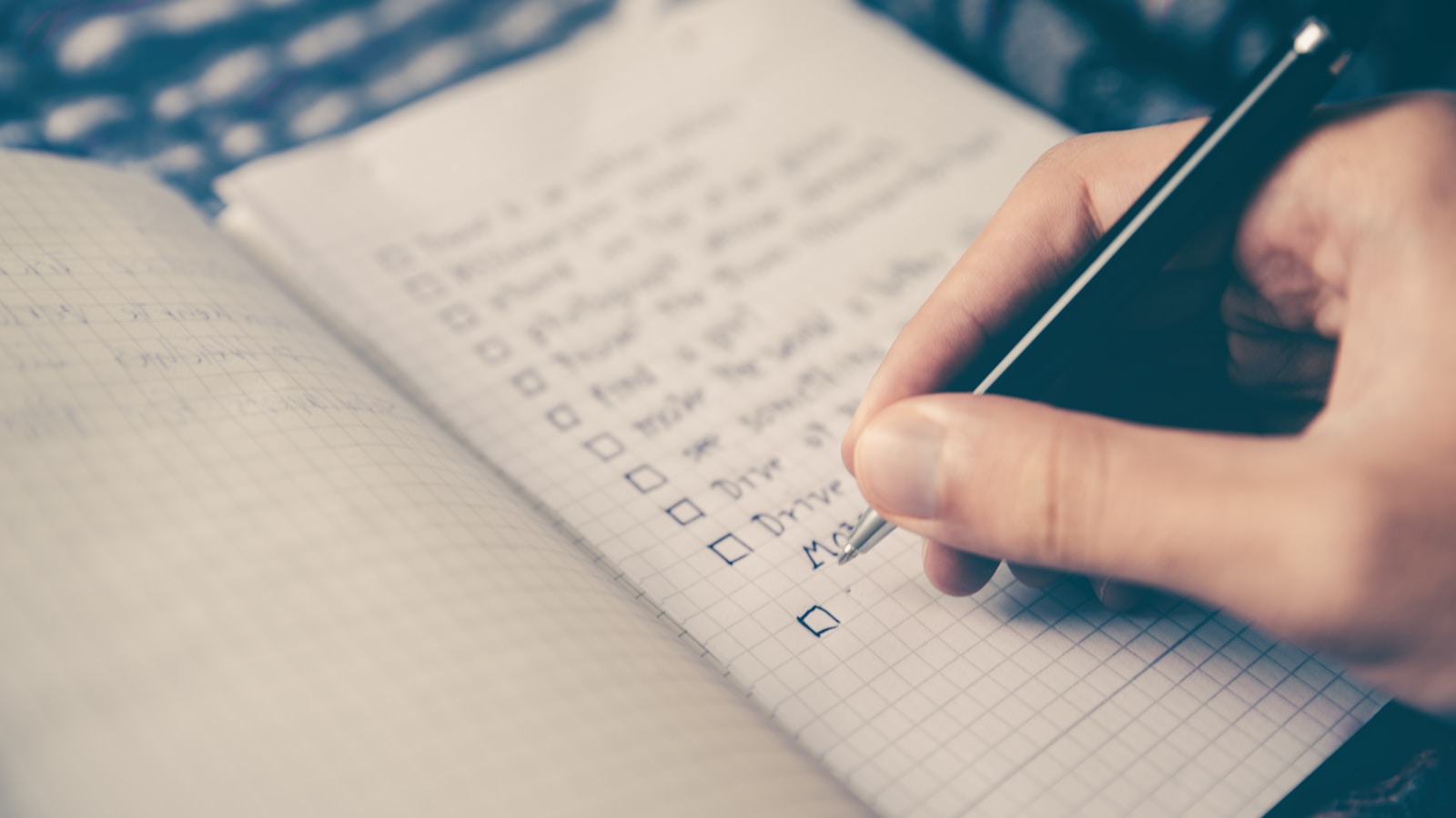 Person writing a checklist in a notebook while planning a link building campaign