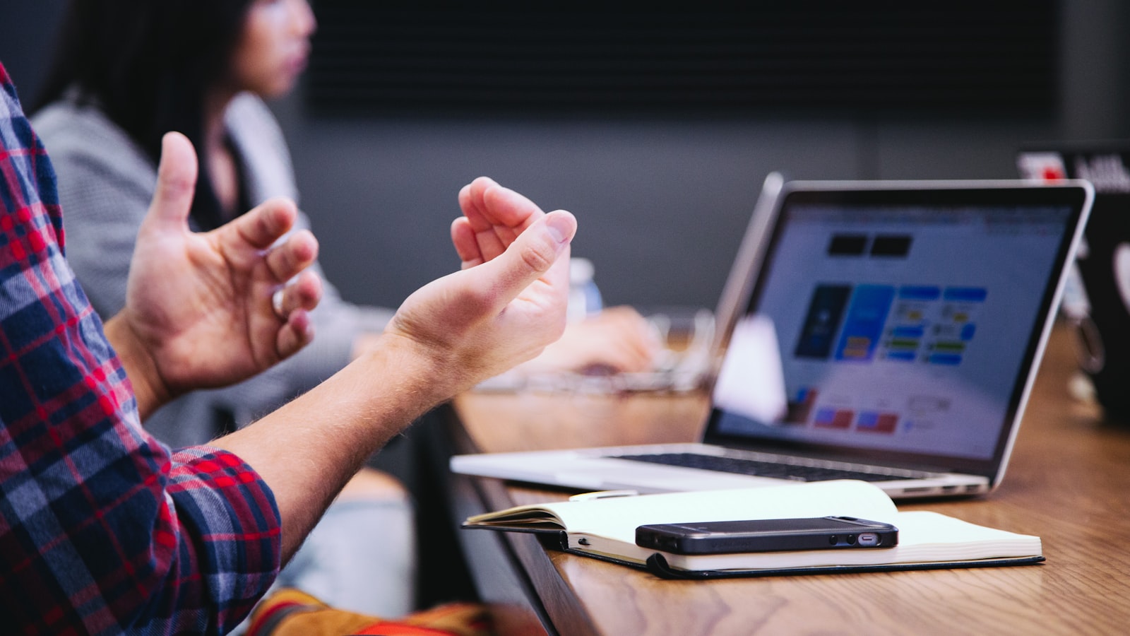 Team member explaining an outsourcing decision during a strategy meeting with a laptop