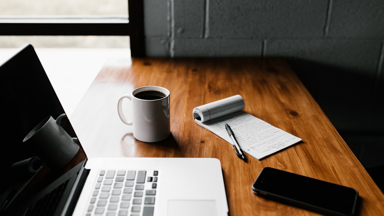 Clean workspace with a laptop, notebook and phone, used for planning a link building strategy
